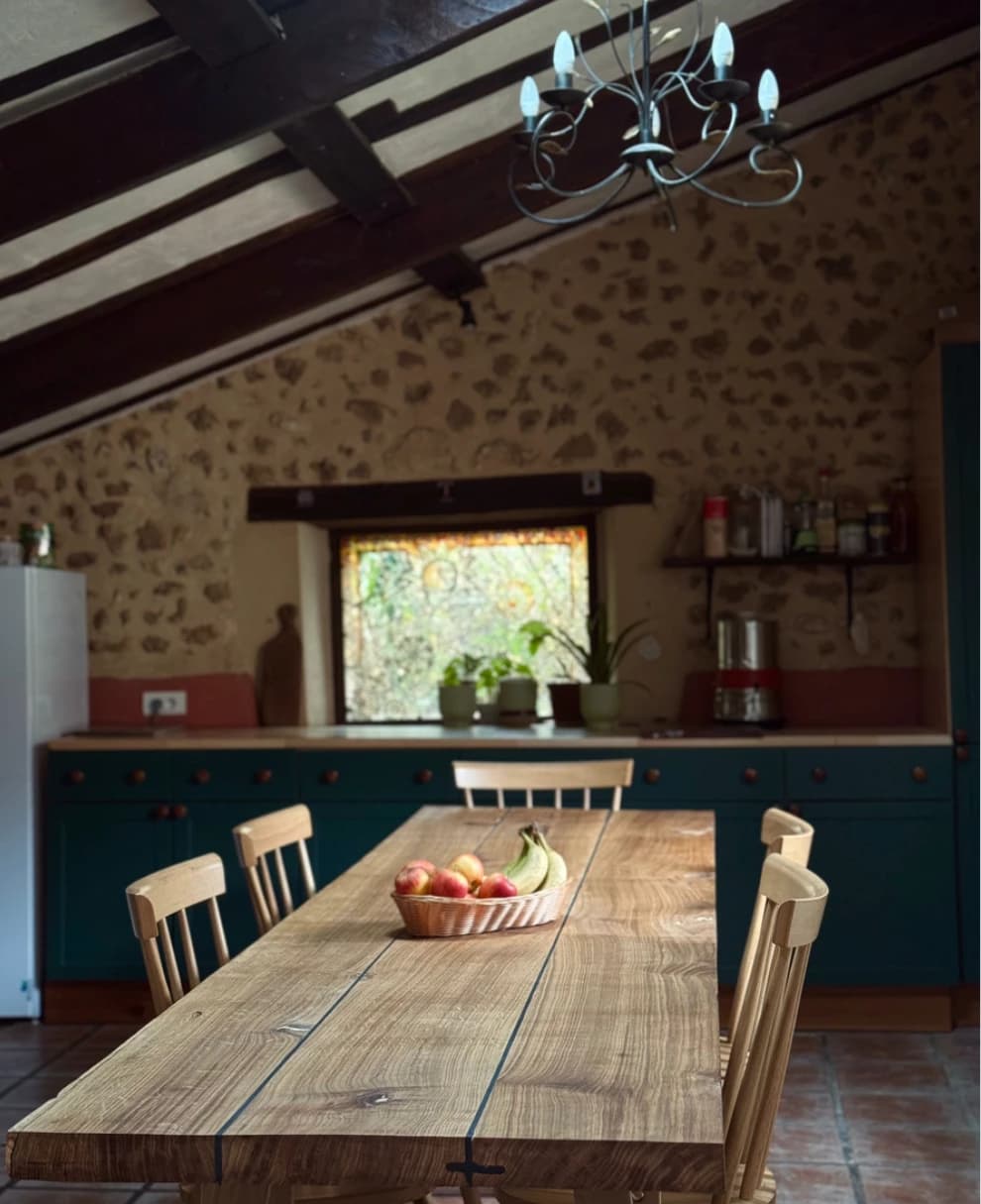 La cuisine aux murs de pierre, lustre en fer forgé et grande table en bois