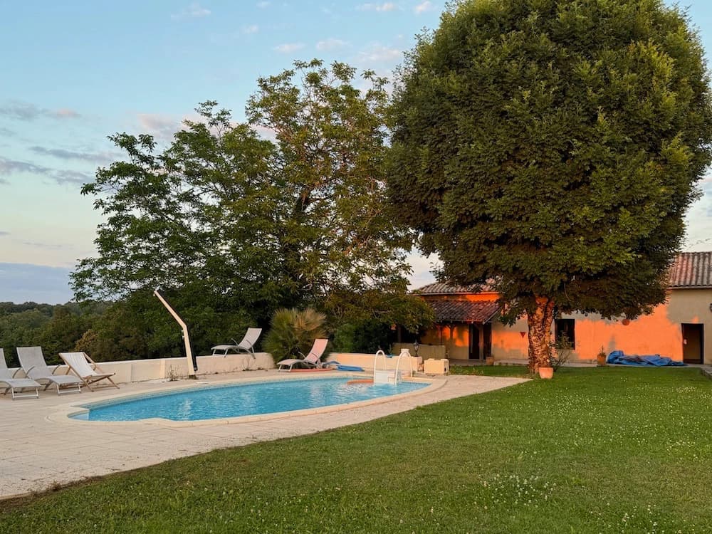 La piscine depuis le jardin, chaises longues à l'ombre de l'arbre
