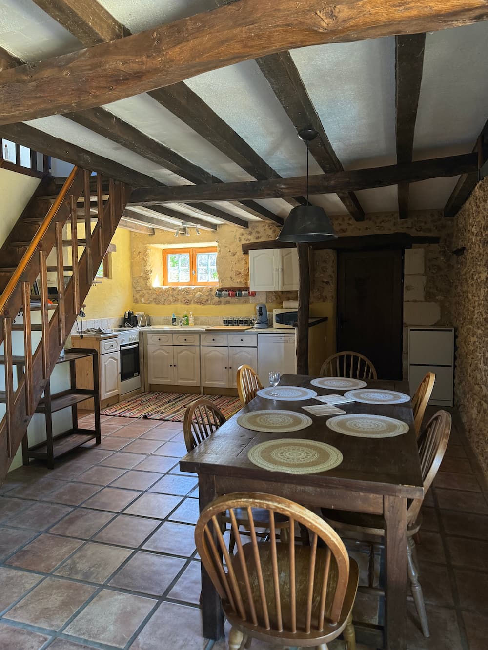 La cuisine aux poutres apparentes, escalier ouvert et table dressée — petite maison