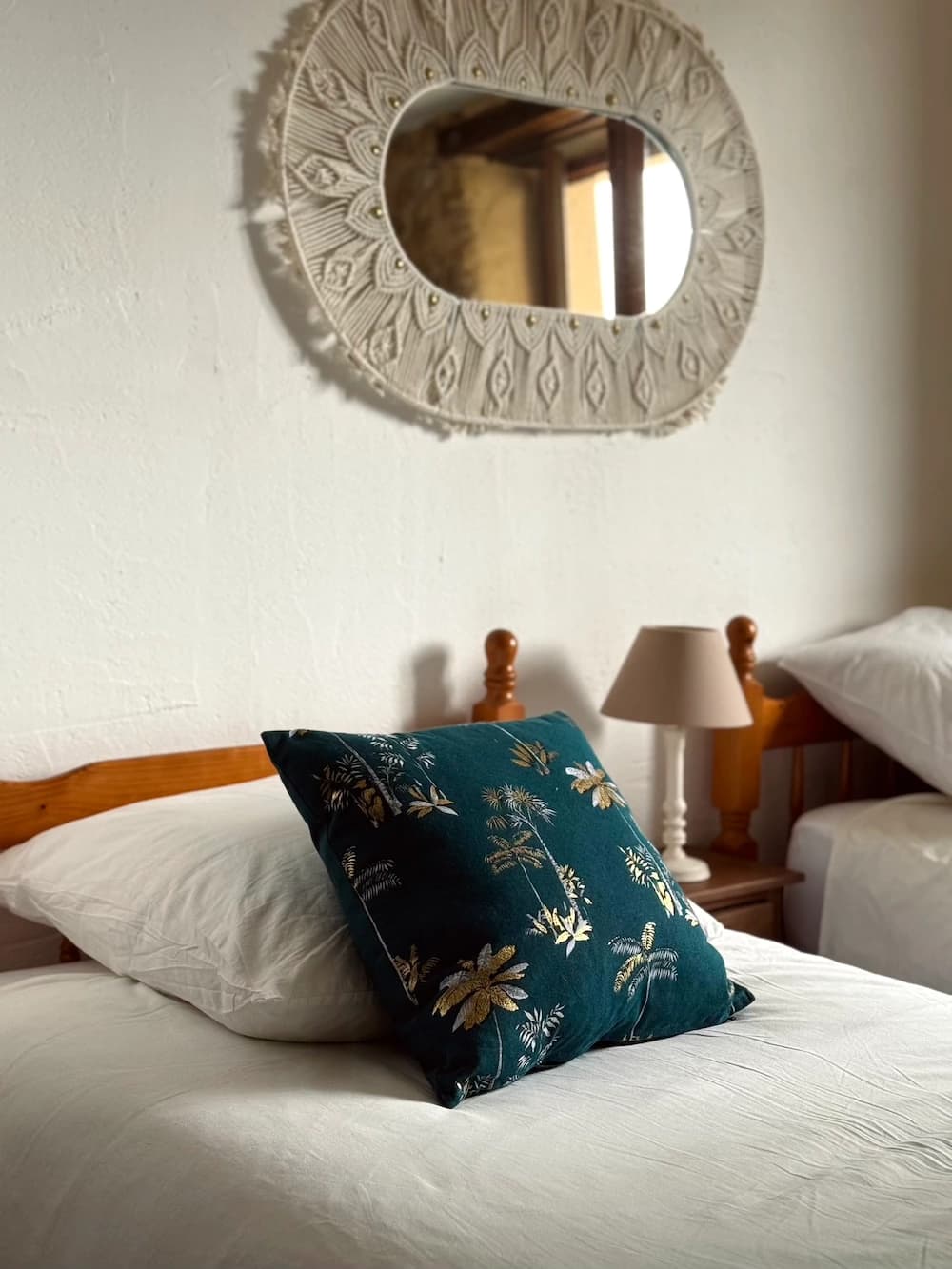 Miroir tressé au-dessus du lit, coussin à motifs floraux