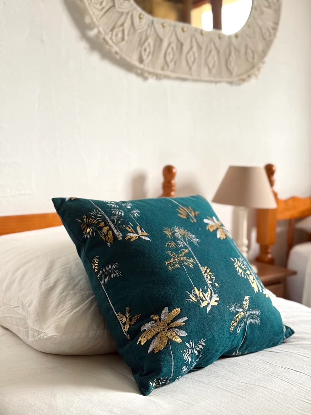 Coussin à motifs feuillage sur linge blanc, lampe de chevet
